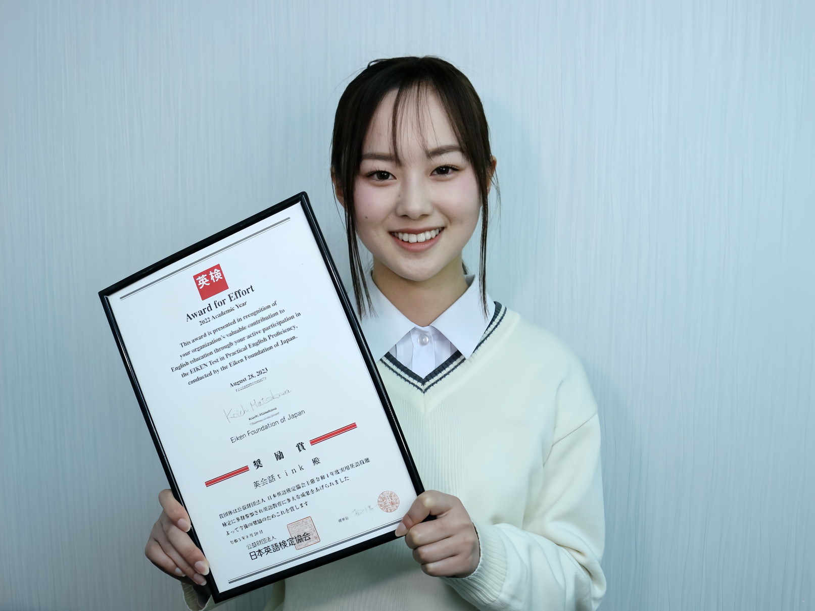 英検合格証を持つ笑顔の生徒